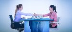 two women sitting at a desk shaking hands with an image of an iceberg overlaid on the desk