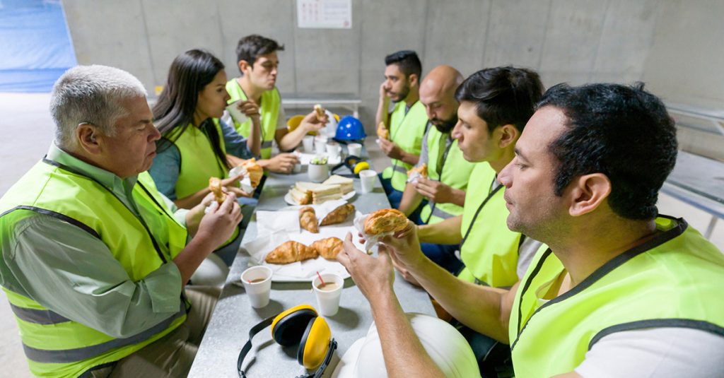 The Work Family Analogy blog image showing a team of construction management professionals eating together as a family